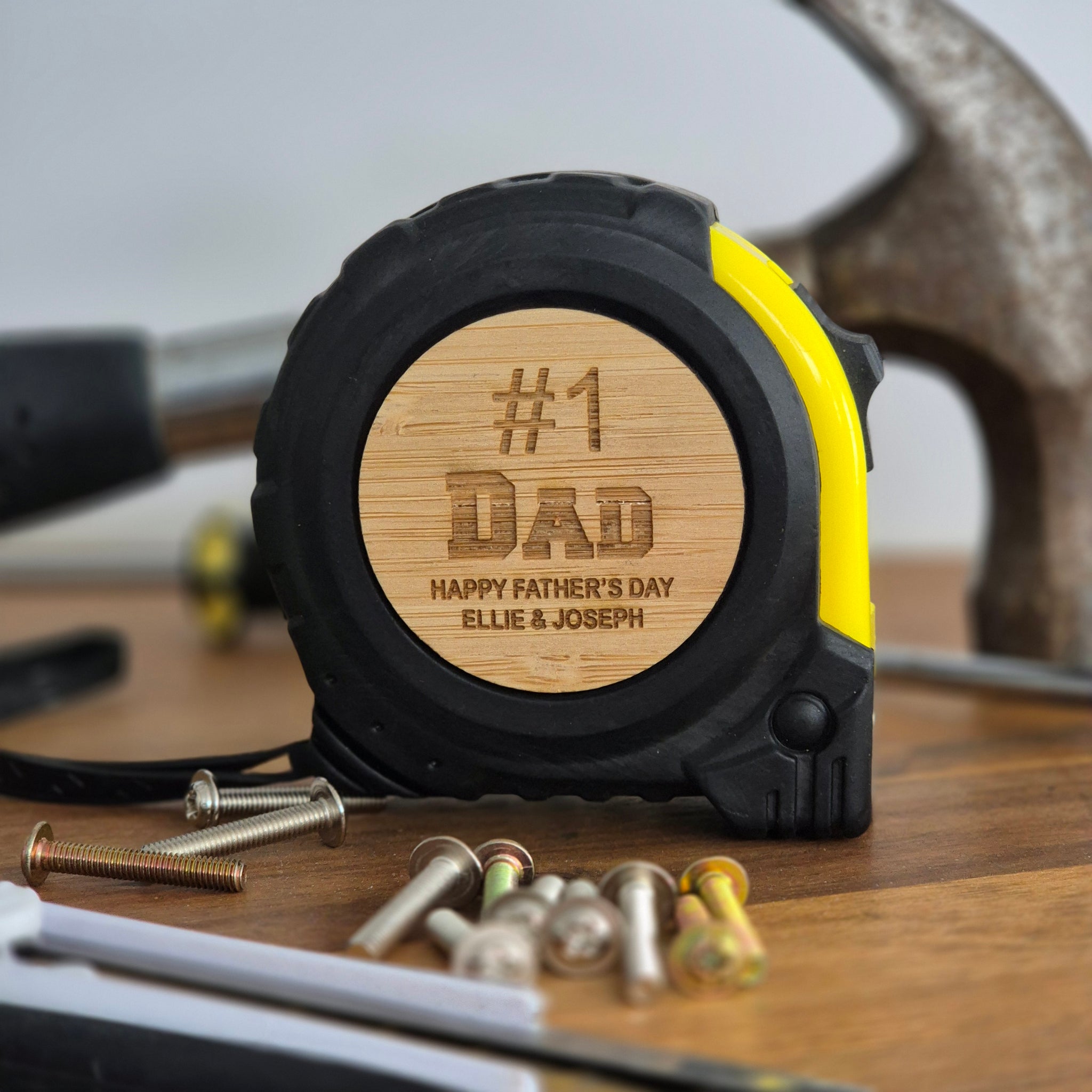 Tape measure with wooden back and engraved text, surrounded by tools on a white background