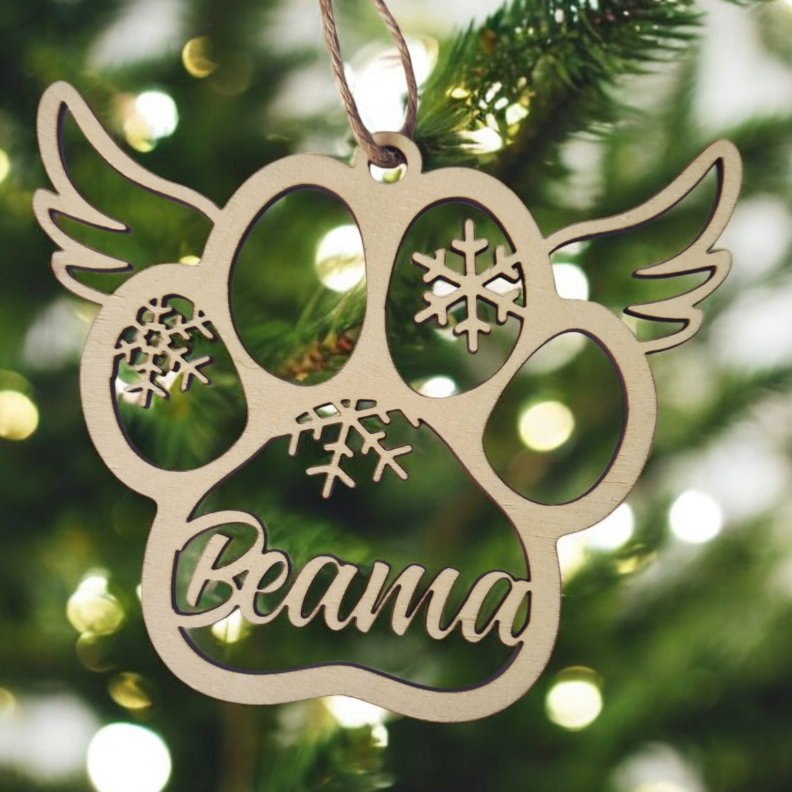 Decorative paw print ornament with 'Beama' on a Christmas tree.
