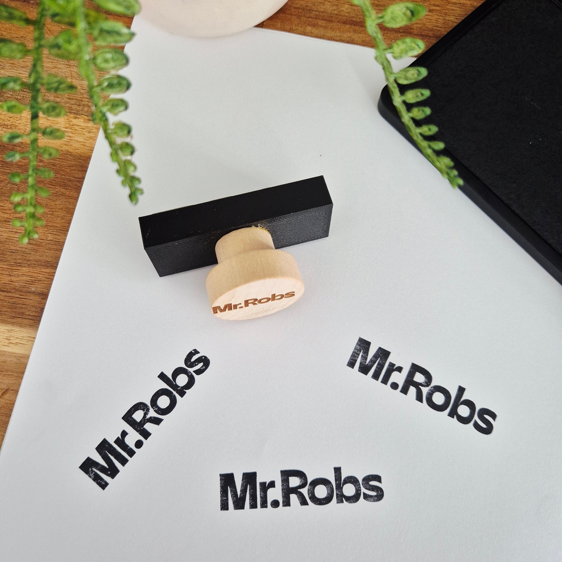 Wooden stamp with 'Mr. Robs' branding on a white surface with printed text.