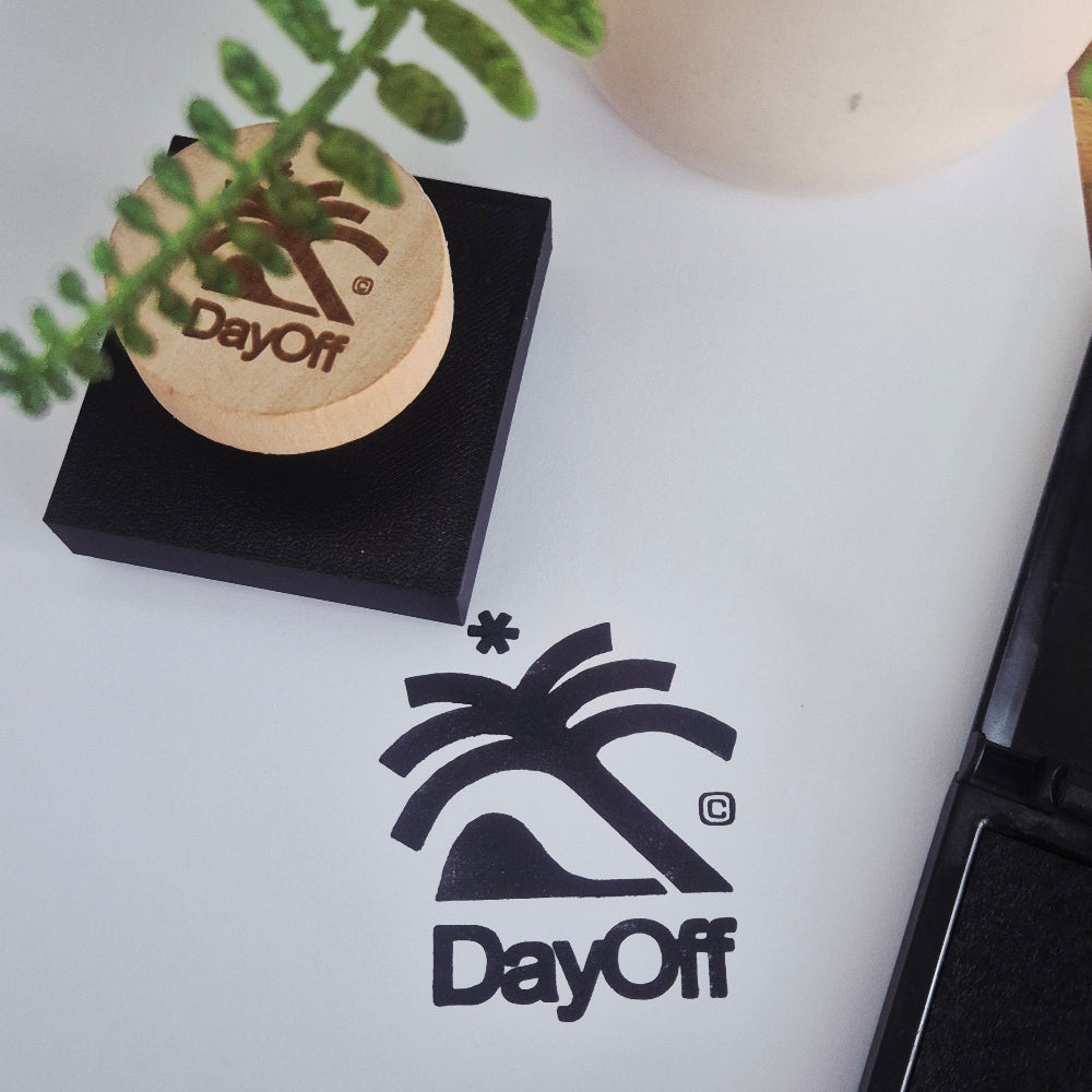 Dayoff logo on a white surface with a plant and black box in the foreground