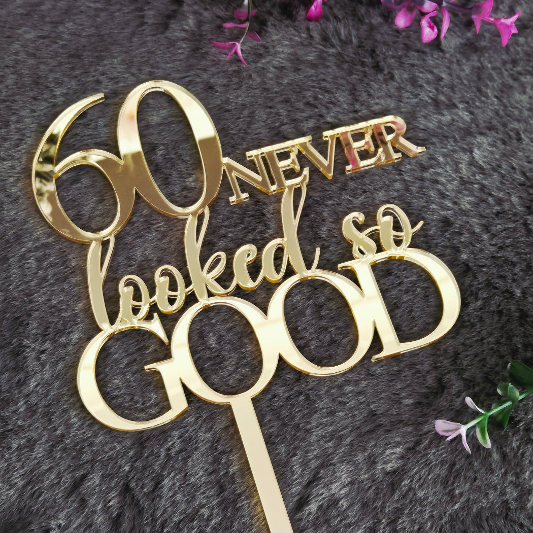 Gold cake topper with 'Never' and 'Forever' text on a dark surface with flowers.