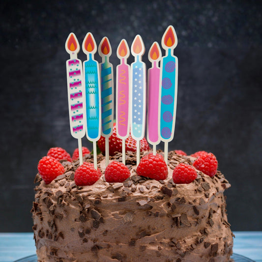 Chocolate cake with raspberries and colorful candles on a dark background