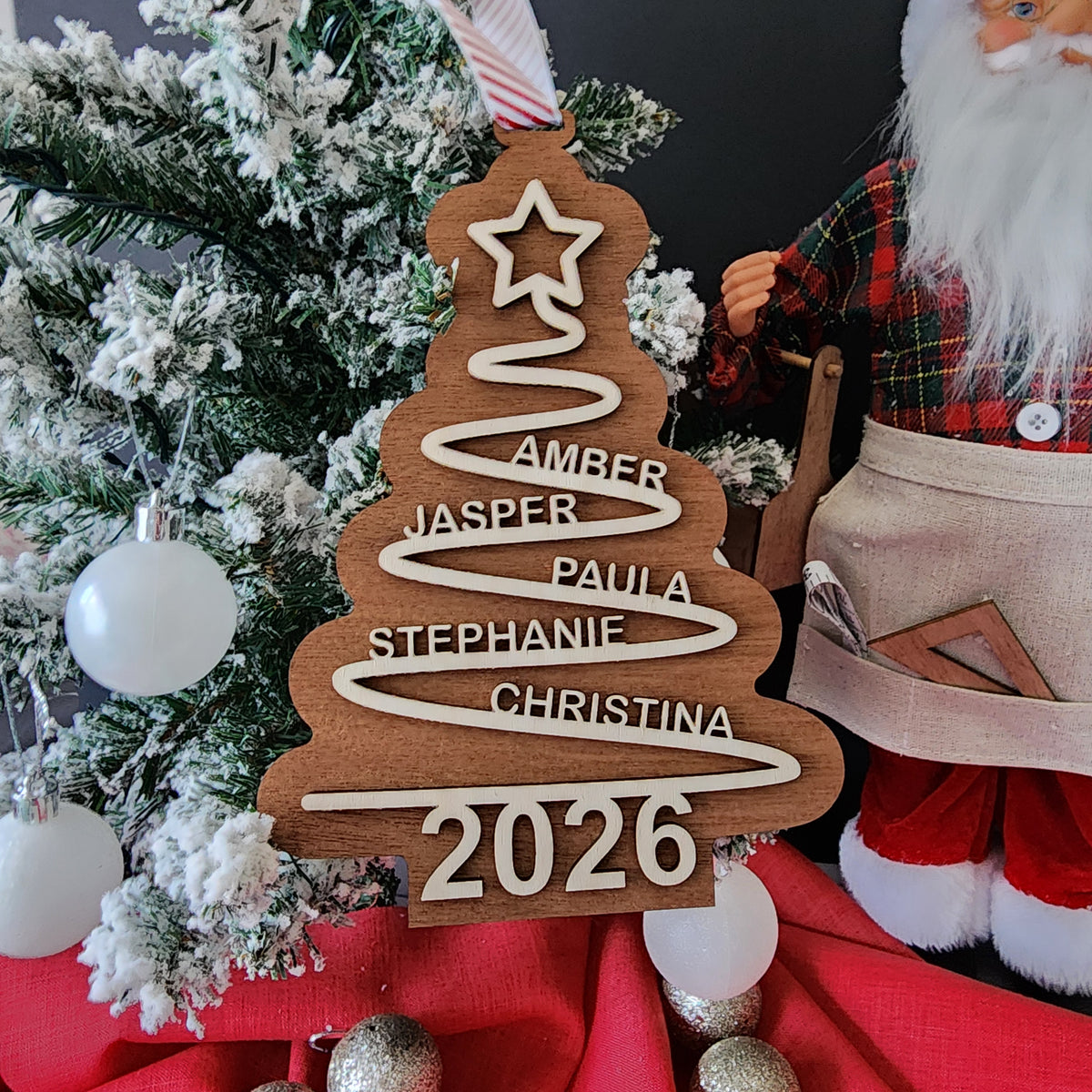 Personalised wooden family Christmas tree ornament with custom names and year 2026 hanging with red striped ribbon