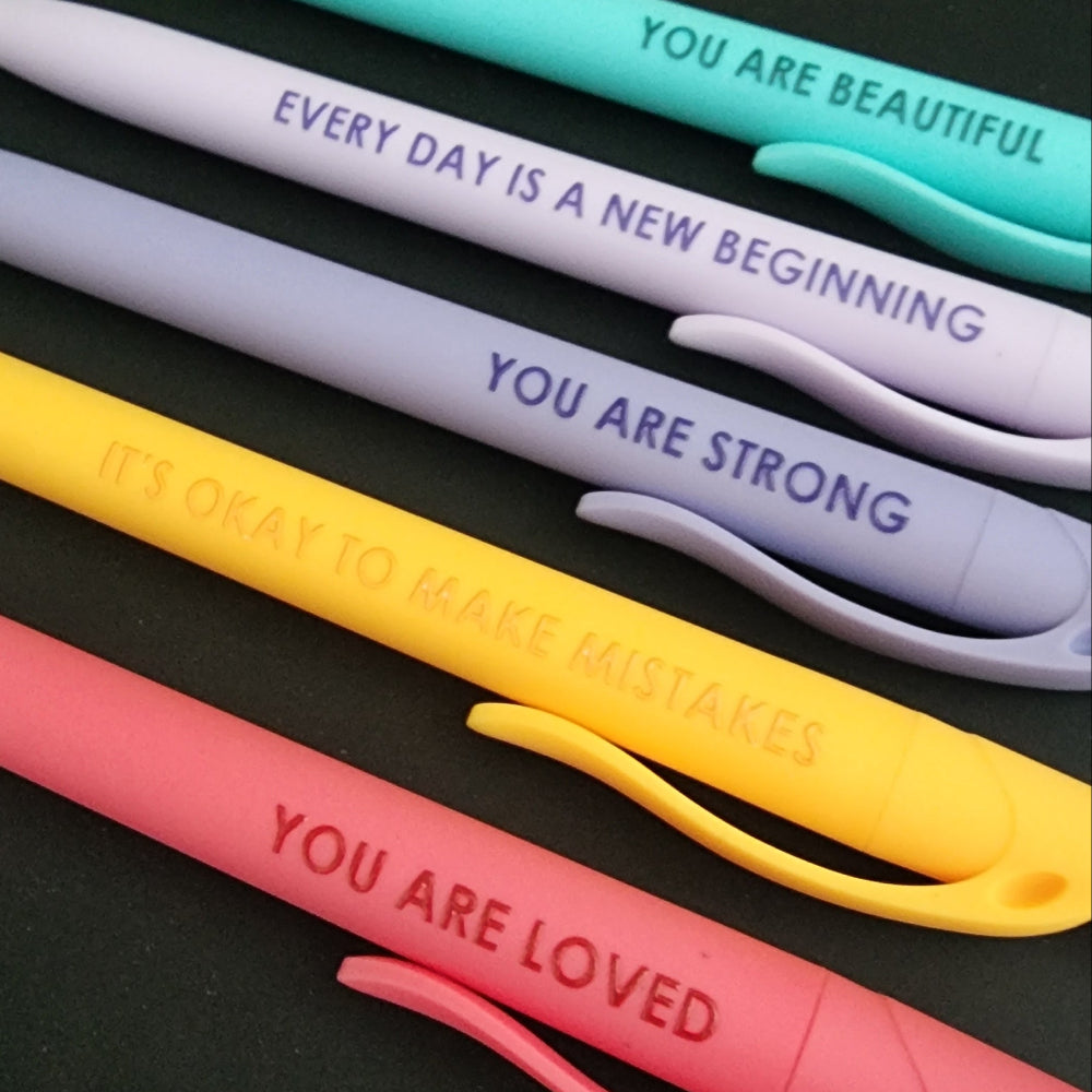Close up of pastel yellow and coral pink affirmation pens reading It's Okay To Make Mistakes and You Are Loved