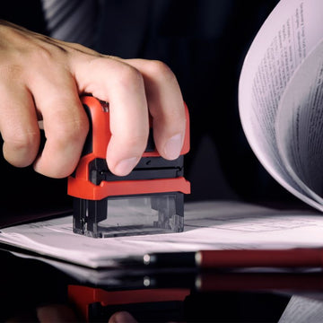 Image of a legal professional stamping a self inking stamp onto documents