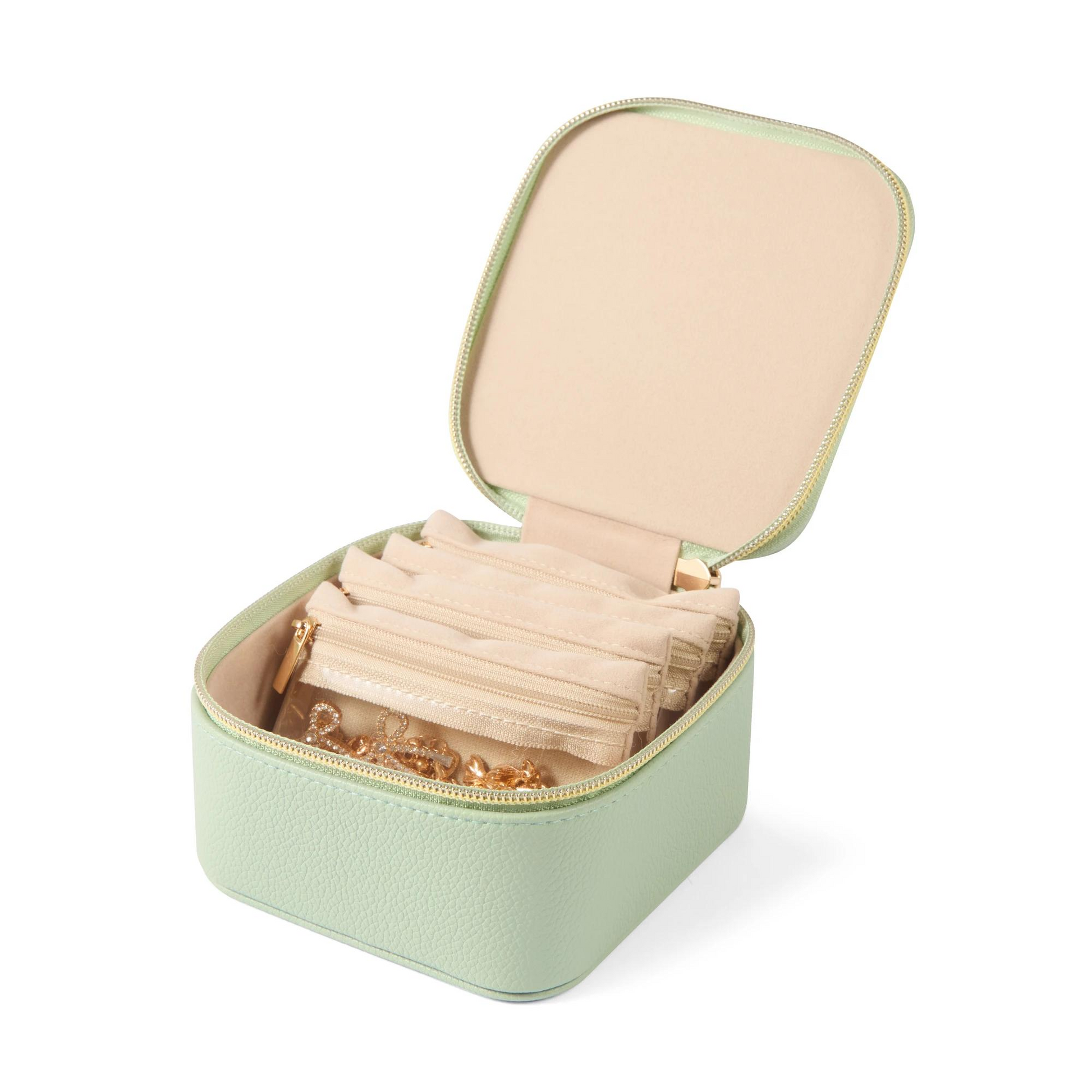 Green jewelry case with beige interior containing jewelry on a white background
