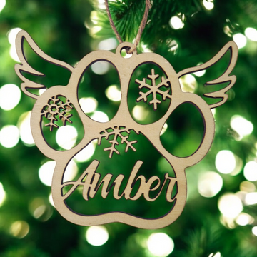 Decorative ornament with paw print design and 'Amber' engraved, hanging on a Christmas tree.