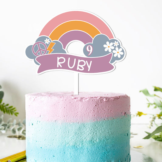 Pink and blue cake with a rainbow-themed cake topper on a white background