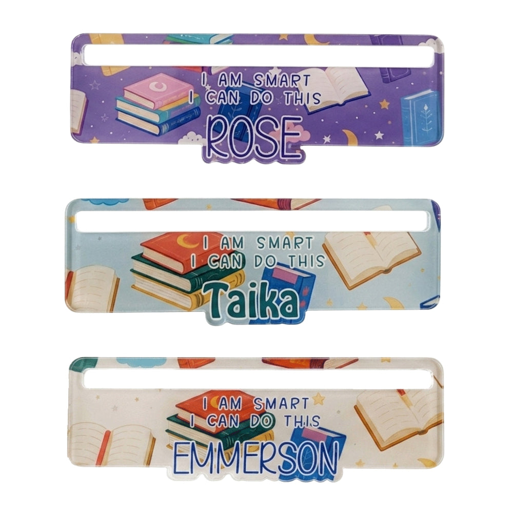 Three personalised nameplate signs with a school-themed graphic of books, stars, and the text 'I AM SMART I CAN DO THIS'. The names printed are Rose, Taika, and Emmerson.