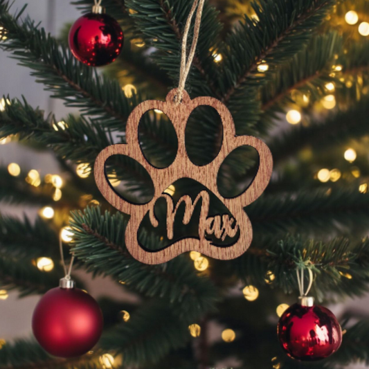 Personalised wooden paw print Christmas ornament laser cut with the name Max hanging on a Christmas tree.